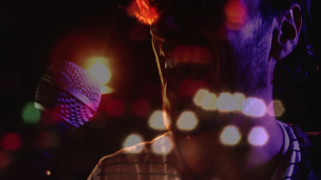 Cantante uomo che inizia a cantare, si china verso il microfono, canta per lo studio mentre una luce di contorno e un effetto bokeh si sovrappongono al viso.