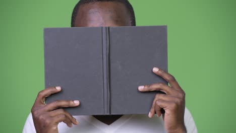 young african man covering face with book