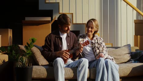 couple playing ukulele in their new apartment