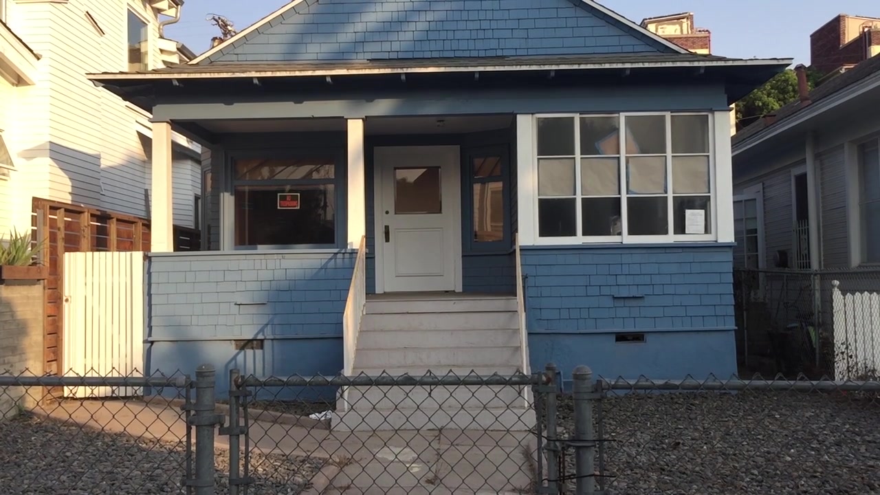 Slow motion Pan of a fenced in blue house in Venice Beach, California on a hot summer's day.