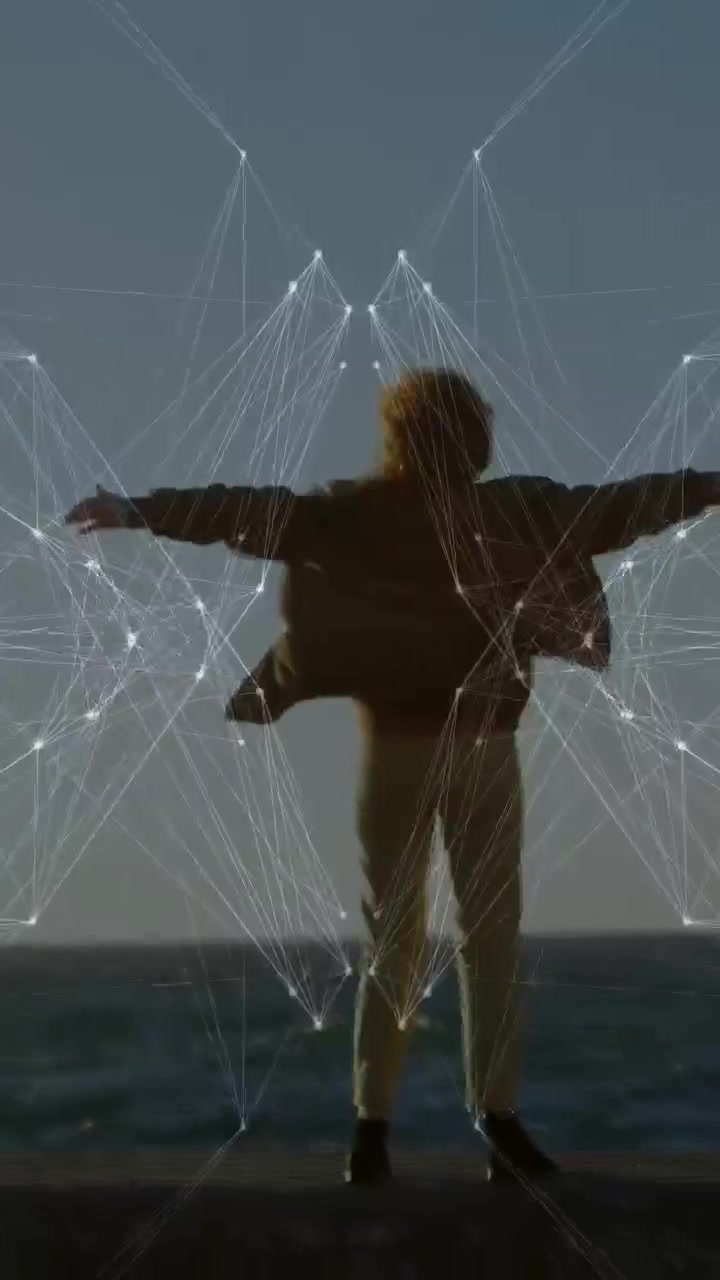 Vídeo vertical: Mulher estendendo os braços em um píer, com uma esfera brilhante descendo e formando asas tecnológicas.