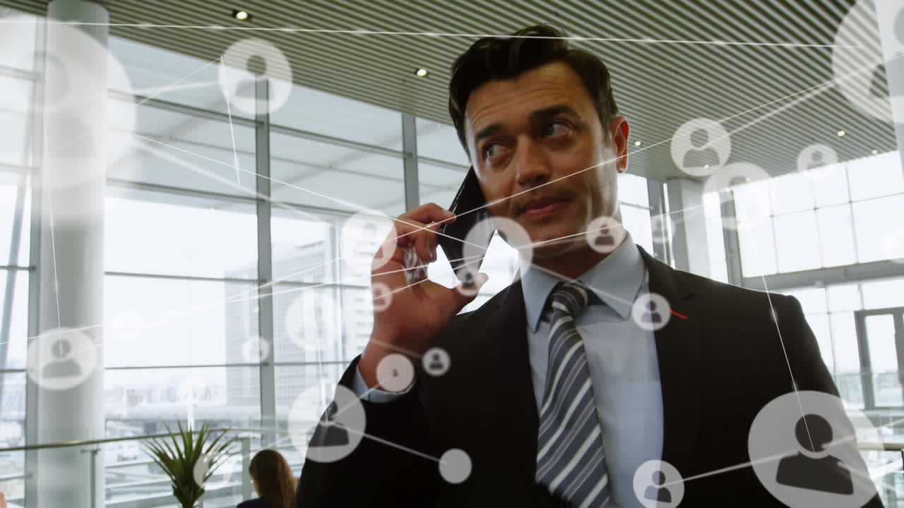 Animation of network of profile icons over caucasian businessman talking on smartphone at office