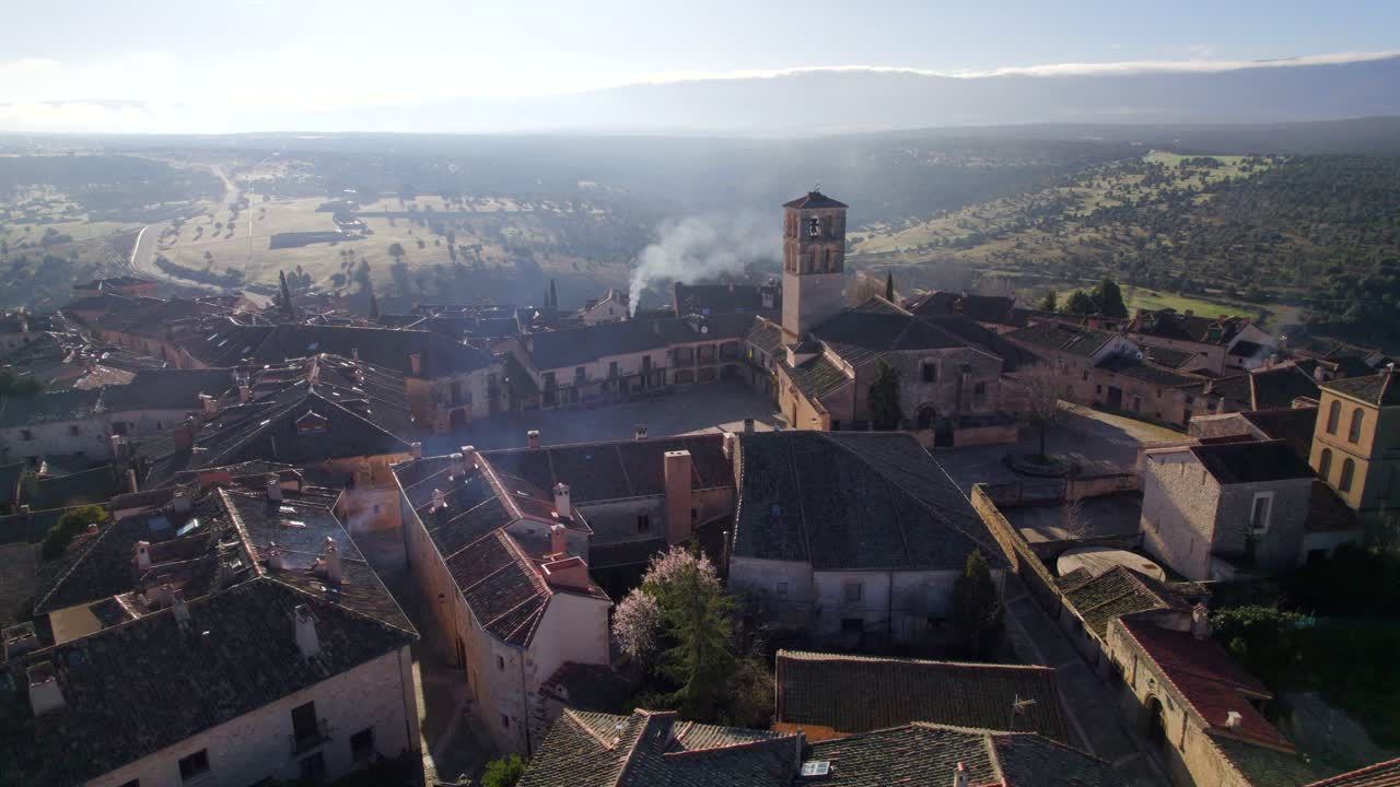 vista aérea cinematográfica de 4k sobre el pueblo medieval español de pedraza mientras sale humo de una chimenea