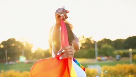 una mujer sonríe y sostiene una bandera de orgullo arco iris