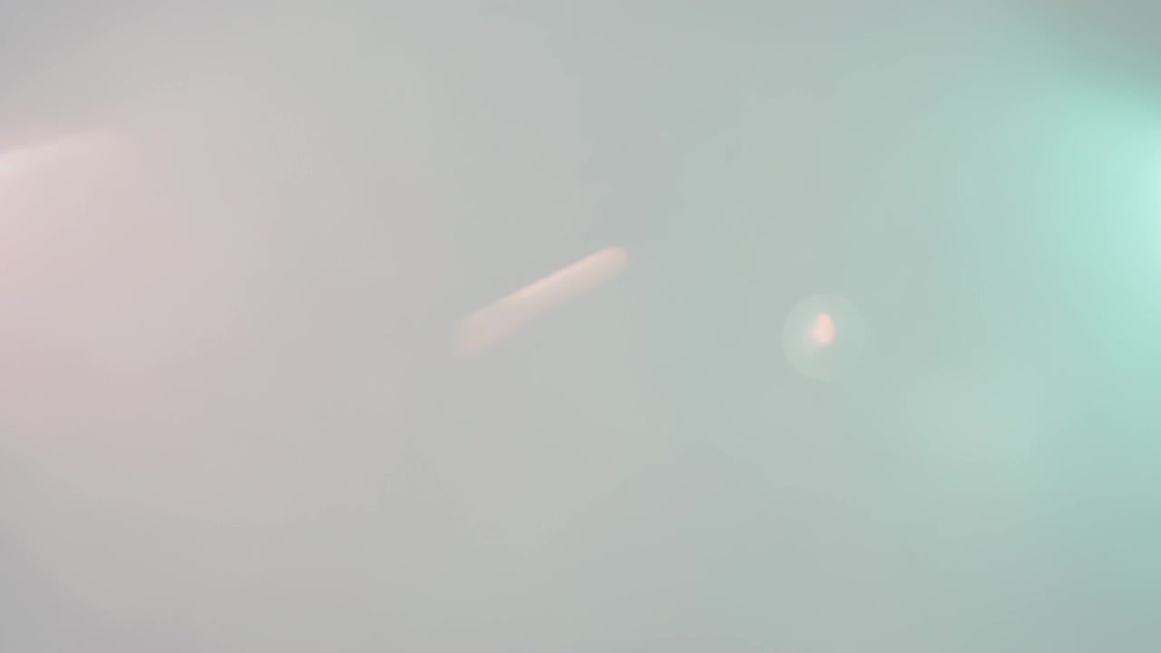 Showing pale-pink streak brightening and drifting in studio, with lens flare, teal glow, haze