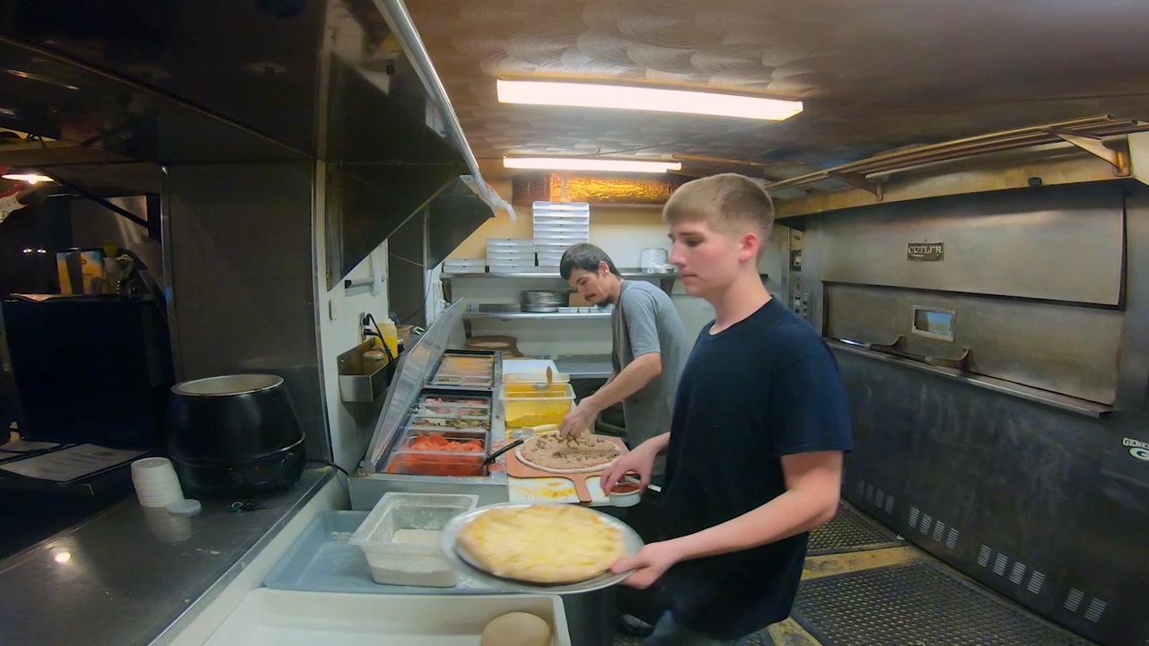Personale di cucina che prepara pizze nella cucina di una pizzeria-ristorante a conduzione familiare