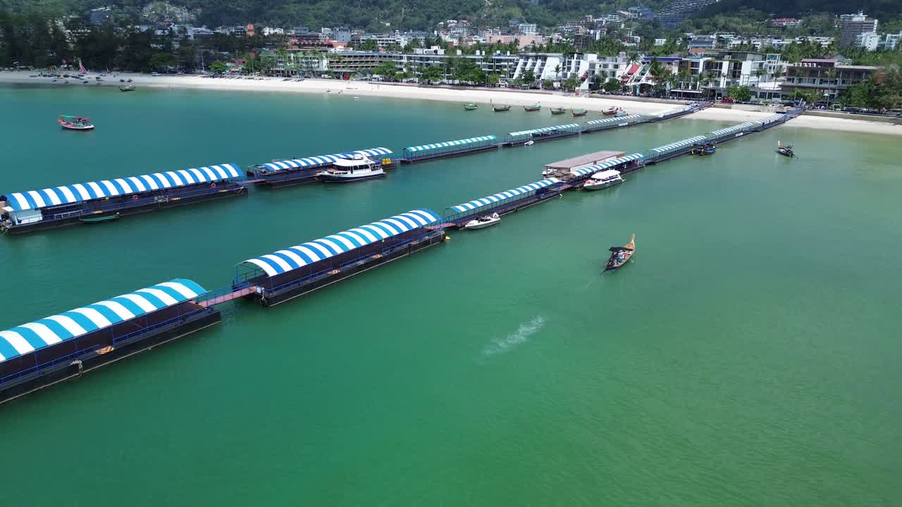 Drone flies forward and pans slowly down as a boat arrives at the pier in Patong, Phuket. The skyline and horizon fade into the distance, creating a cinematic coastal view.