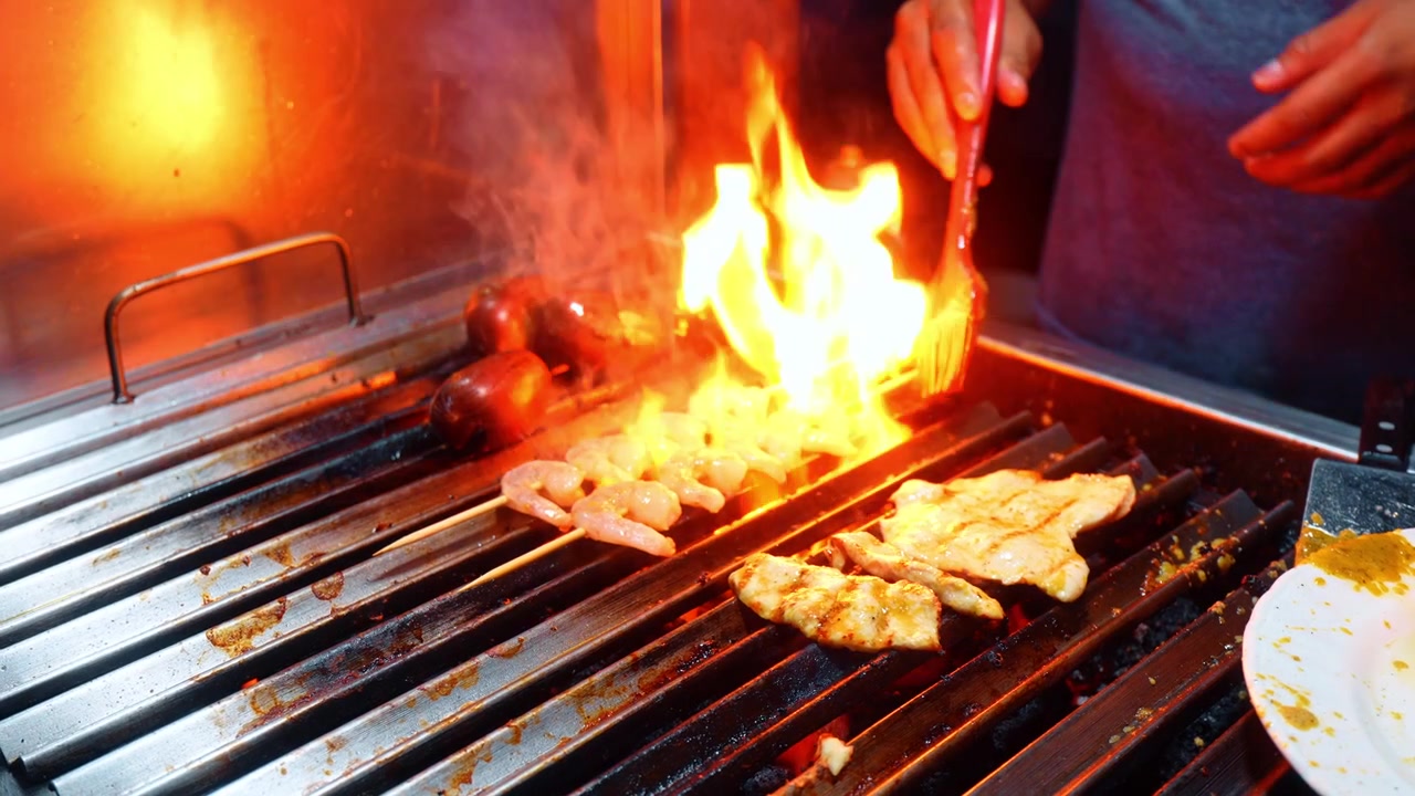 Grigliata di Gamberi e Pollo alle Galapagos. Spiedini di gamberi e pollo marinato su griglia metallica su braci ardenti senza fiamma viva, salsiccia, sfondo scuro e suggestivo, cibo da strada Isabela Galapagos