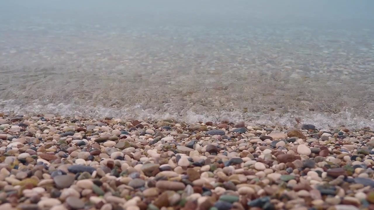 Ondas Suaves Lavando Seixos Lisos em uma Praia