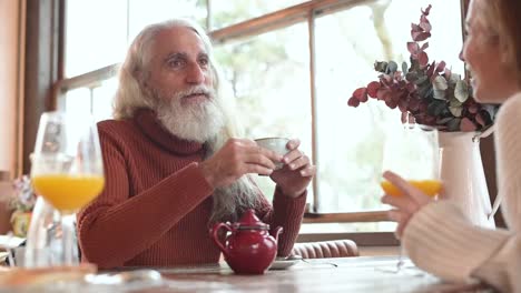 cheerful man talking to unrecognizable partner in cafe