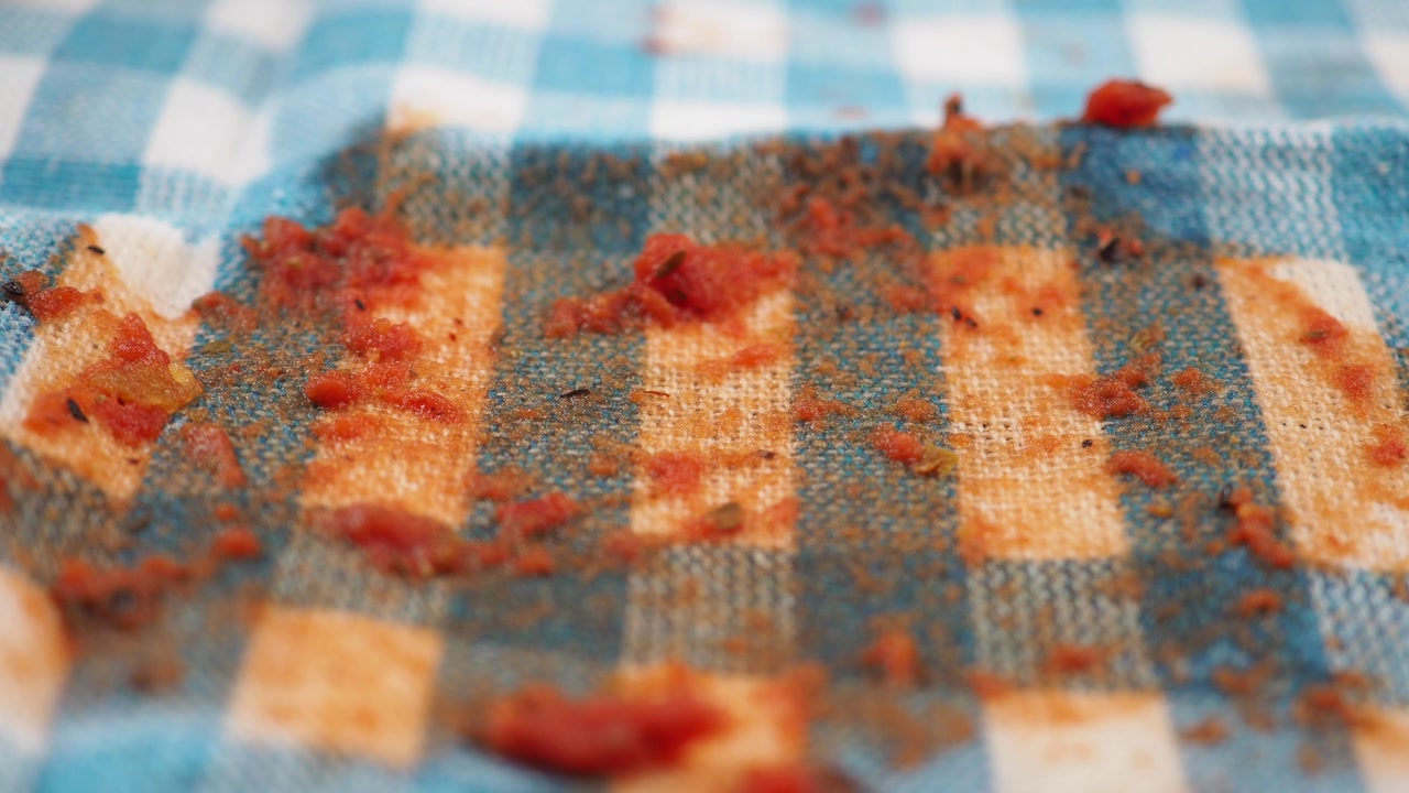 Spilled Tomato Sauce and Crumbs on a Dirty Checkered Tablecloth
