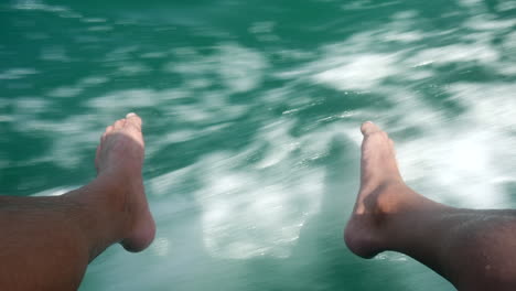 men feet hang from the boat down into the water from the sea in croatia istria