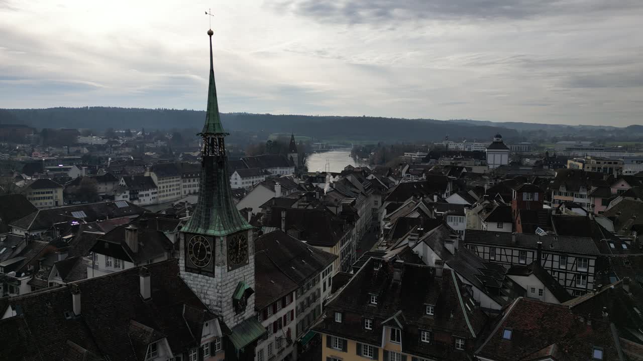 Veduta aerea di una storica città europea con un'imponente torre campanaria di una chiesa e un fiume