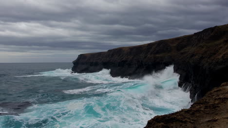 powerful ocean waves crashing against rocky cliffs under a stormy sky
