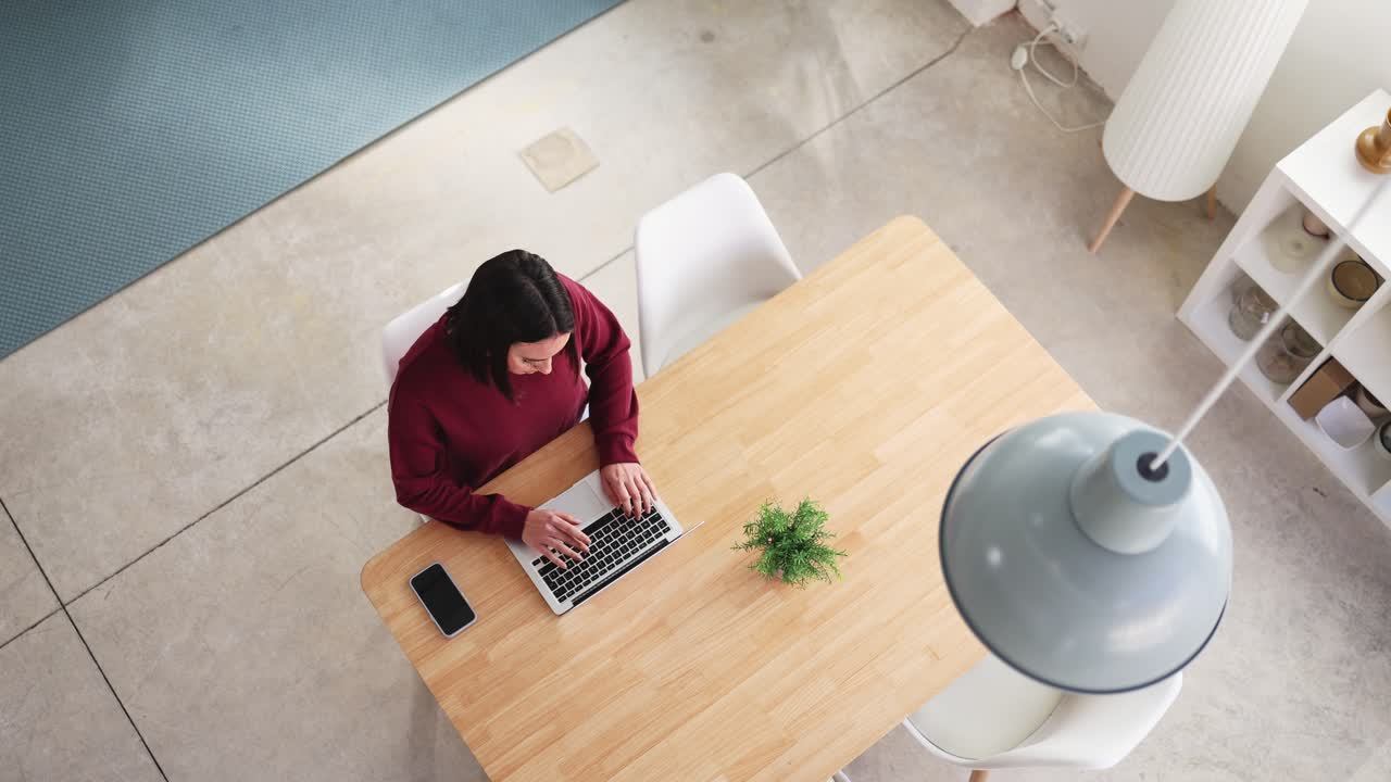 Young Woman Sits Down and Starts Working on Laptop at Modern Table