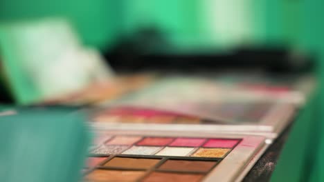 slow motion closeup of cosmetic brush picking colorful powder, green background