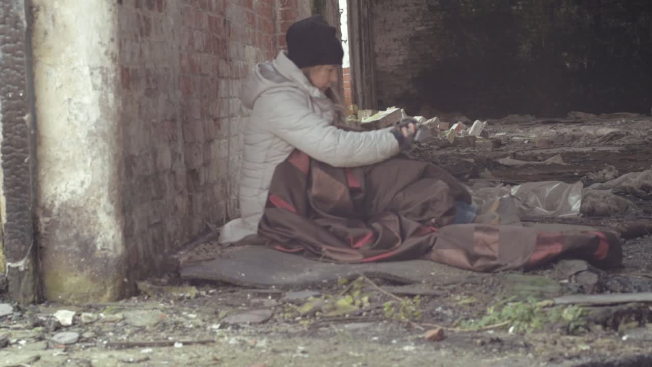 Homeless person in abandoned derelict building trying to keep warm