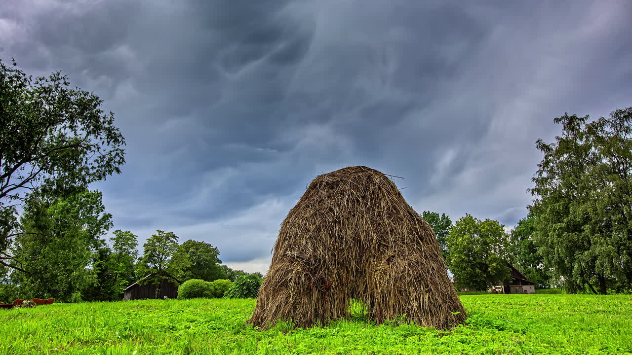 toma de lapso de tiempo de nubes grises dramáticas emergentes en el cielo y pajar en el campo de la granja en primer plano