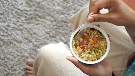 woman eating canned tuna and couscous with vegetables