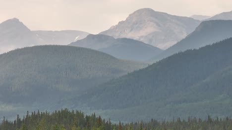 wildfire smoke obscures the rocky mountains as a drone flies right to left in alberta, canada