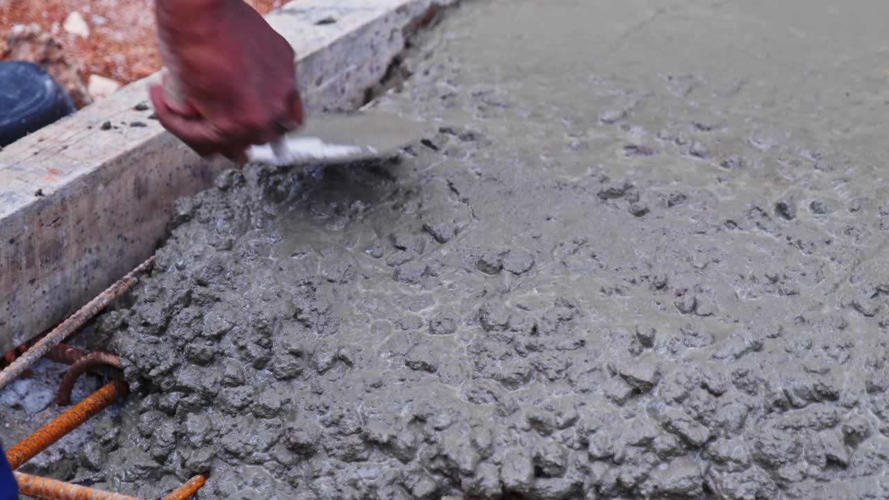 Close-up view of a construction worker using a hand trowel to level and ...
