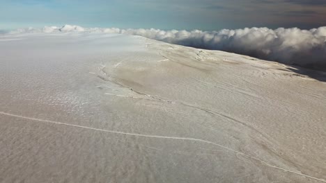 vista panorámica aérea de una grieta en la superficie del hielo de un glaciar islandés, sobre las nubes, en un día soleado y brillante