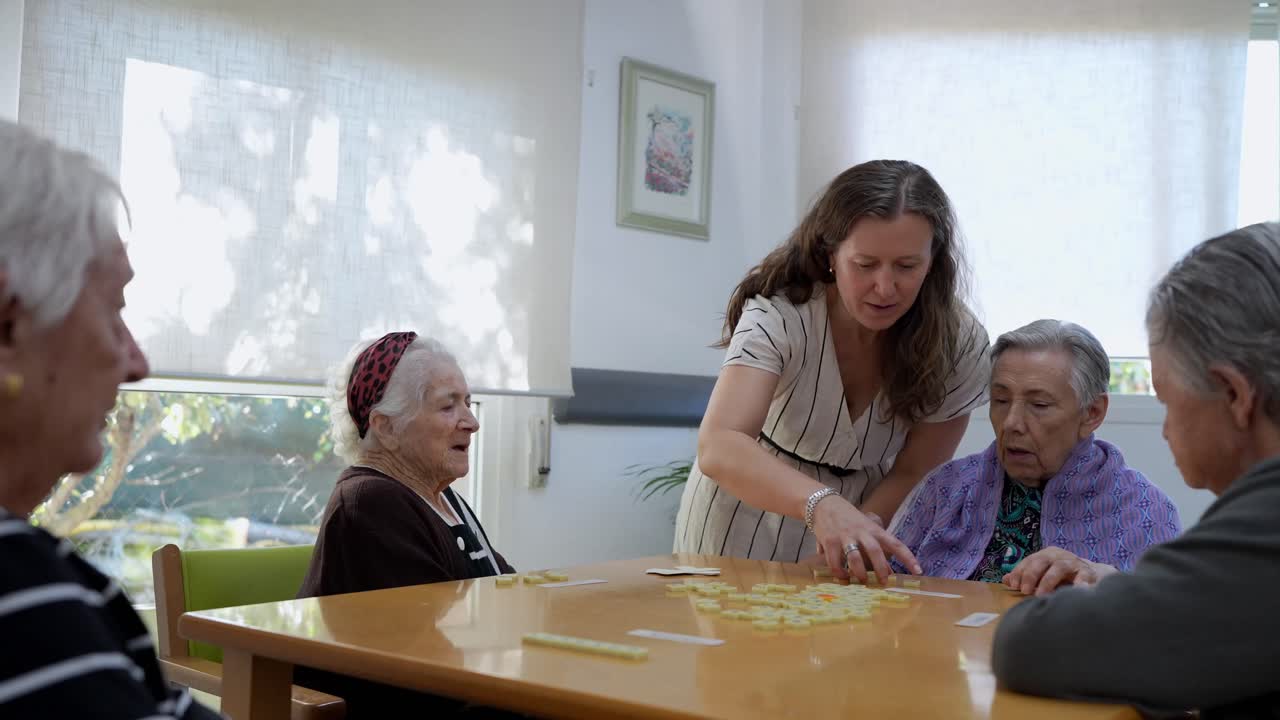 Anziani che giocano a domino con un assistente