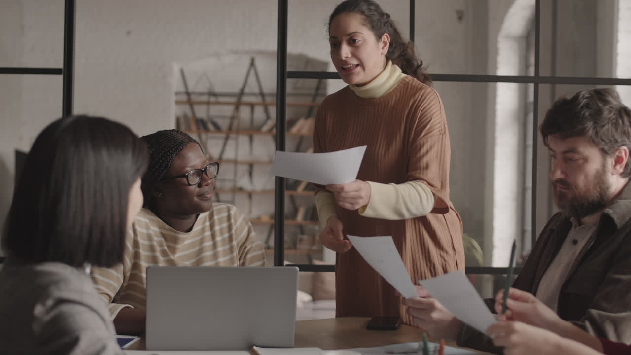 Mixed-Race Woman Giving Documents to Colleagues