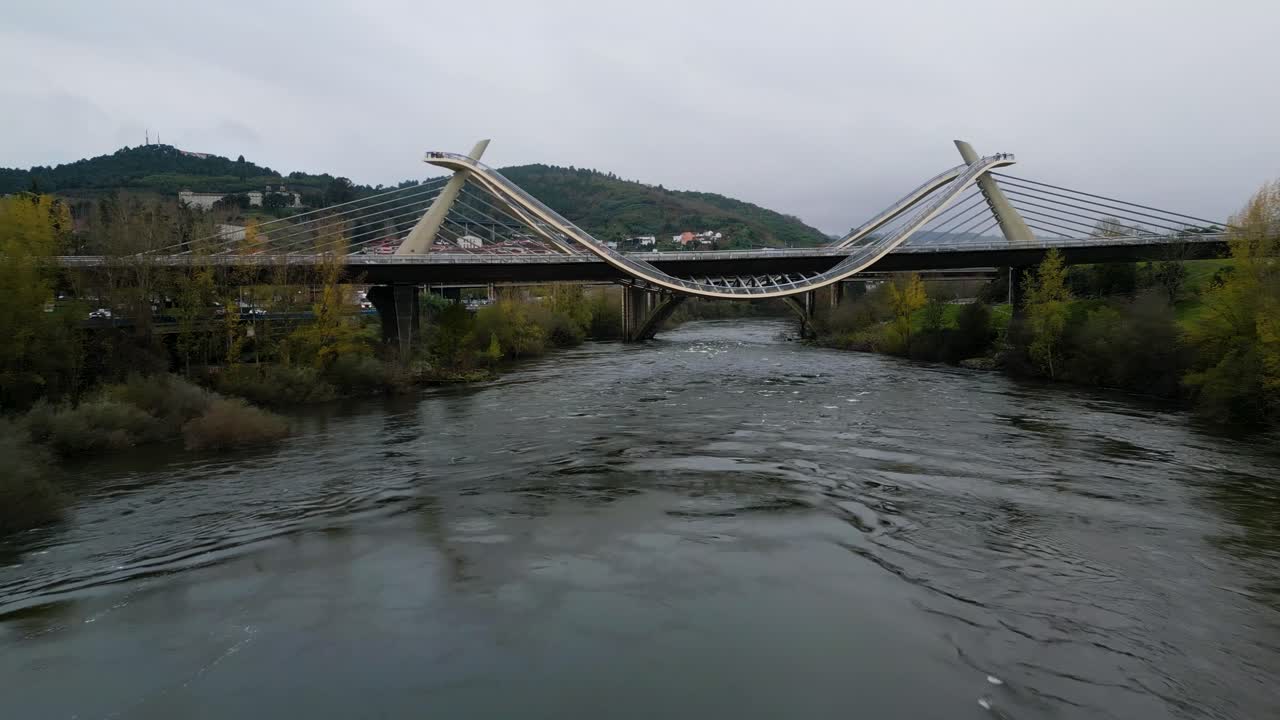 Millennium Bridge over the Mi&ntilde;o River in Ourense, Galicia, Spain, drone dolly below winding path