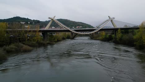 millennium bridge over the miño river in ourense, galicia, spain, drone dolly below winding path