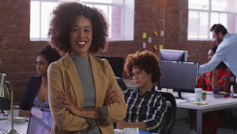 mixed race businesswoman sitting smiling in office room with diverse colleagues in background