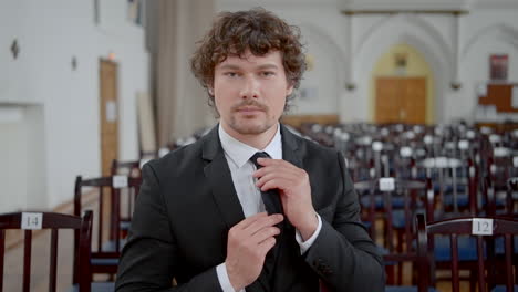 man in a suit adjusting his tie in a large room