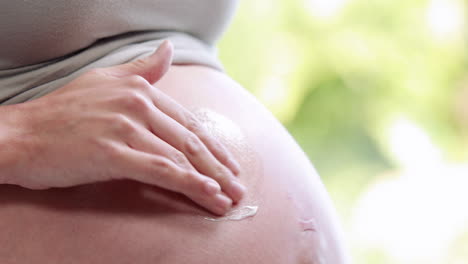 pregnant woman putting lotion on belly