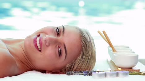 Peaceful-smiling-blonde-lying-on-massage-table-poolside