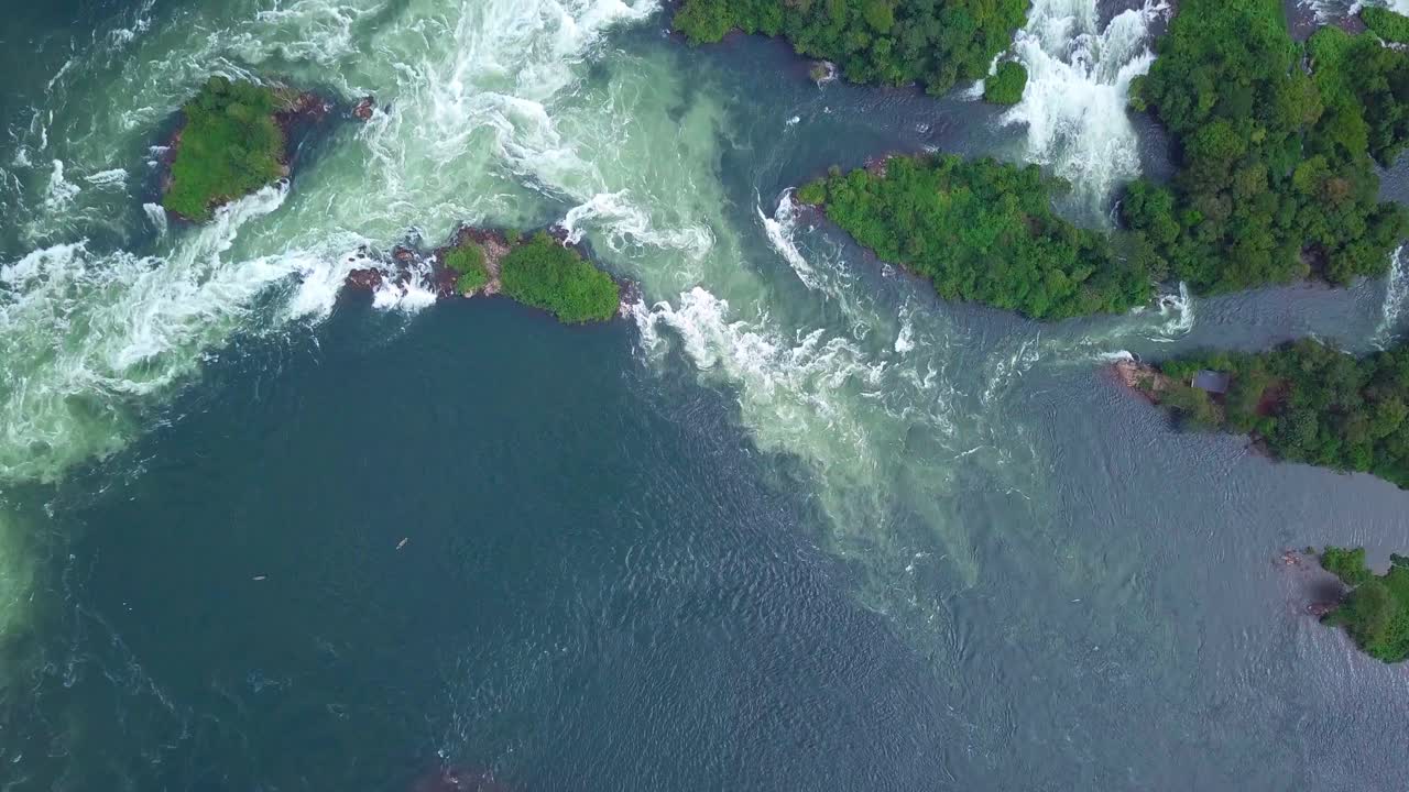 Top down aerial view showcasing the majestic River Nile as it flows through Uganda, Africa, with rapids creating breathtaking waterfalls and lush green islands, a testament to the raw beauty of nature