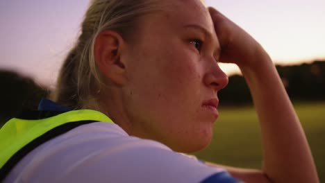 jugadora de fútbol sentada en el suelo en el campo de fútbol. 4k