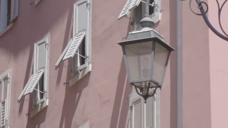close up slowmotion shot of an old lantnern lamp in an alleyway in riva del garda with a rosa building in the background