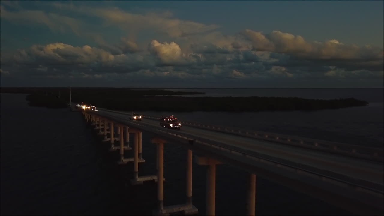 Drone view of a small fire truck driving over one of the many bridges spanning the Florida keys.
