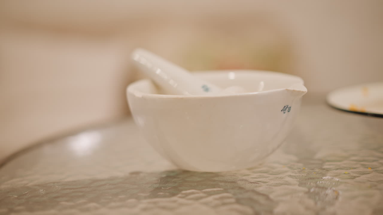 Ambiente de cocina tranquilo con herramientas para especias. Superficie de cristal con mortero y cuenco para la preparación de condimentos. Espacio de trabajo culinario sereno que muestra mortero y plato de cerámica listos para mezclar especias.