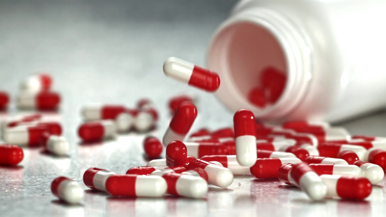 Capsule rosse e bianche che cadono da un flacone di pillole al rallentatore