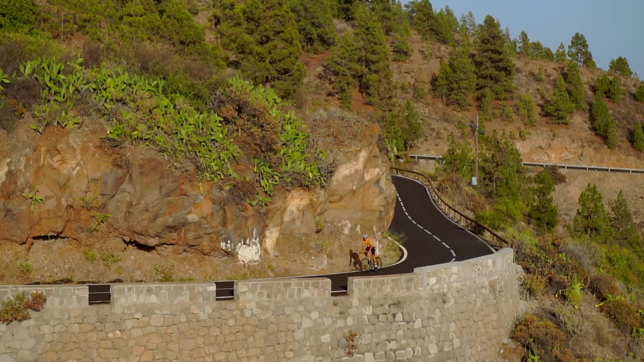 평화로운 아침을 포용하고, 한 남자가 비공개 도로를 따라 도로 자전거를 타고 자전거를 타고 있습니다. 느린 동작 비디오는 극단 스포츠의 본질을 포착합니다.