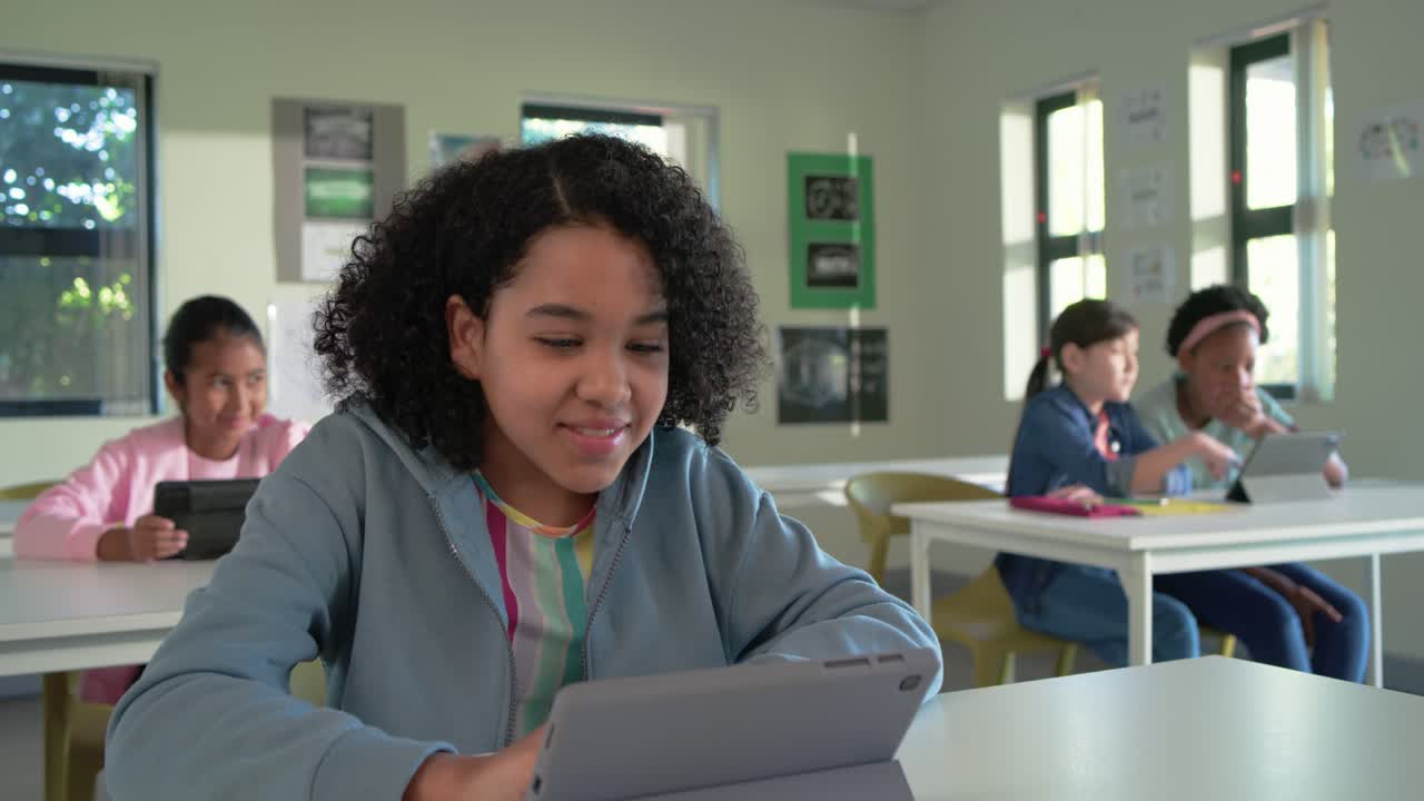 Camera closing in as front African American teen tapping tablet in classroom, studying and smiling