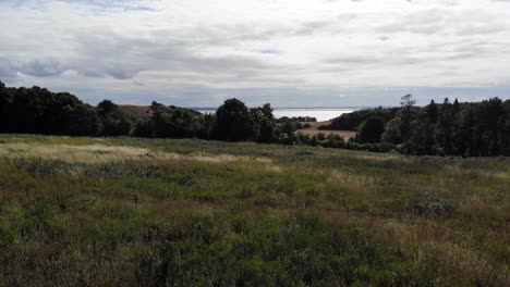 Vista-Aérea-De-La-Costa-De-Sejerøbugten-Con-Colinas,-Campos-Y-Océano