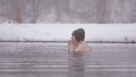 A-happy-woman-sits-in-an-icy-lake-focussing-on-her-breathing,-Sweden