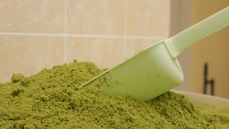 a green scoop of a pastry chef's blade sticks out in a pile of green shredded pistachio seed. dolly shooting pistachio flour in a bowl on the table. turkish baklava production. 4k video