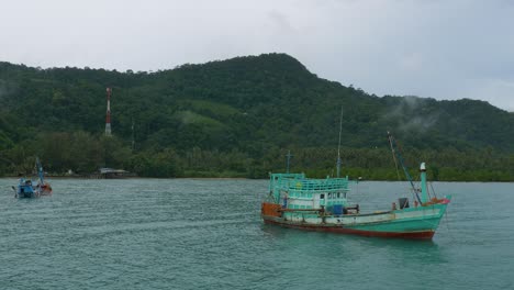 wooden fishing boat towing a half sunken boat behind