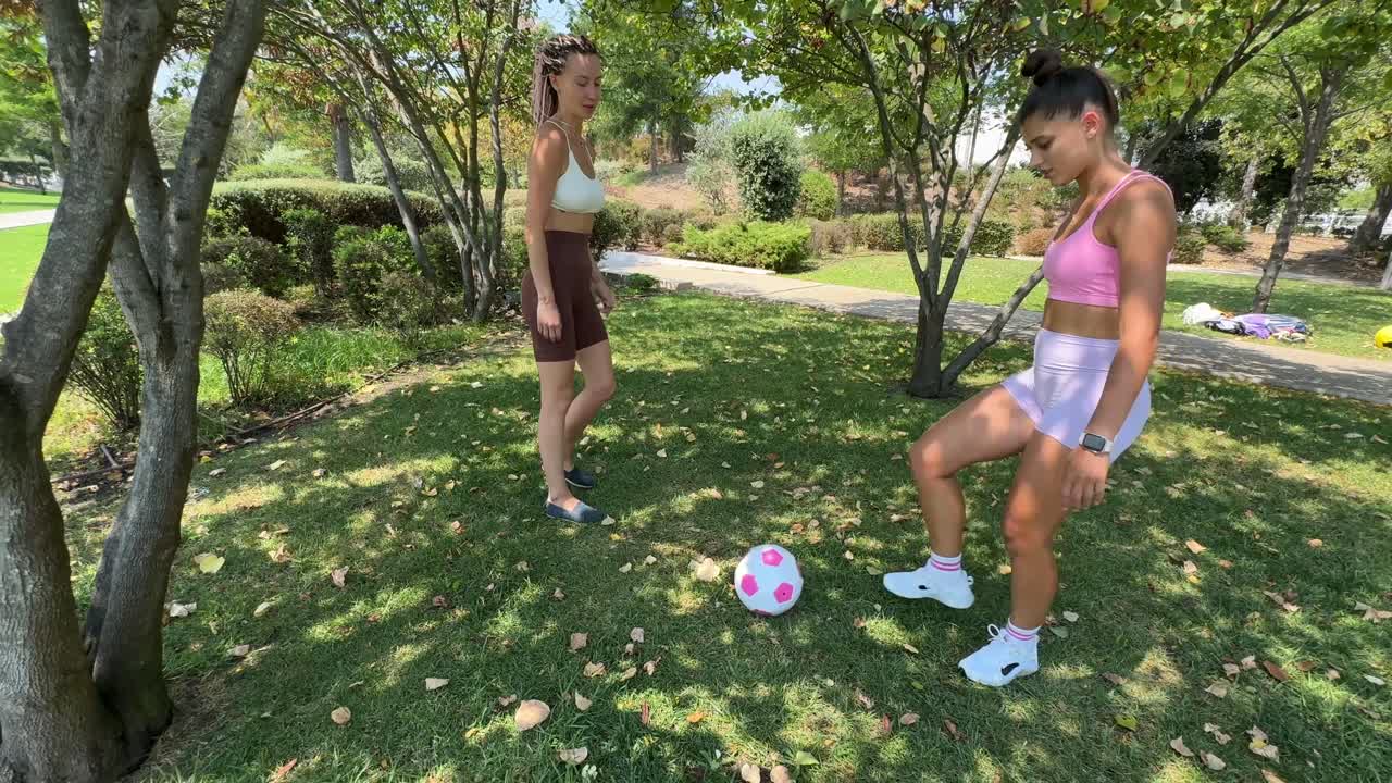 Two women playing soccer in the park
