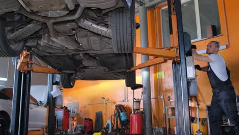 mechanic working on a car lifted in an auto repair shop