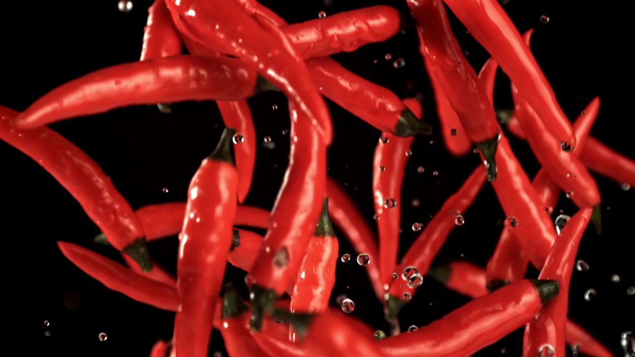 Fresh Red Chili Peppers Falling with Water Drops on Black Background