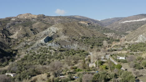 ladera montañosa con cielos azules y casas escasas diseminadas alrededor